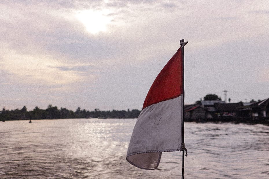 red and white flag on pole near body of water during daytime